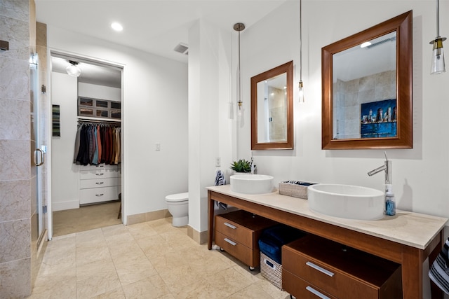 bathroom featuring toilet, walk in shower, and vanity