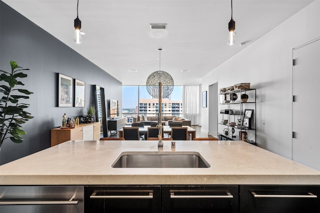 kitchen featuring an island with sink, hanging light fixtures, and sink