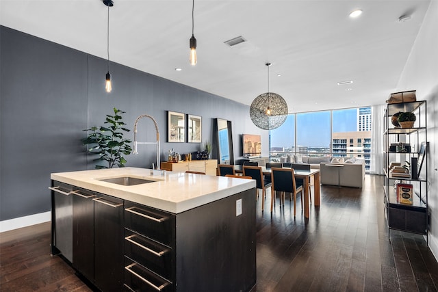 kitchen with pendant lighting, dark hardwood / wood-style floors, a kitchen island with sink, and sink