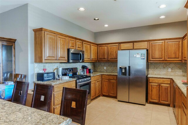 kitchen featuring light stone counters, appliances with stainless steel finishes, and backsplash