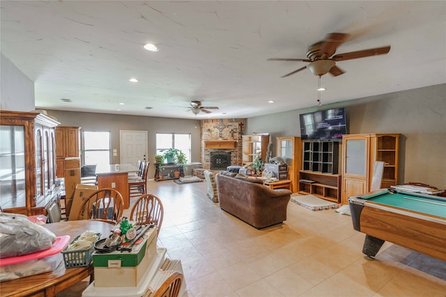 interior space featuring pool table, ceiling fan, a stone fireplace, and light tile patterned floors