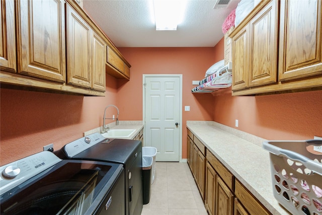 laundry room with cabinets, a textured ceiling, sink, and washing machine and dryer