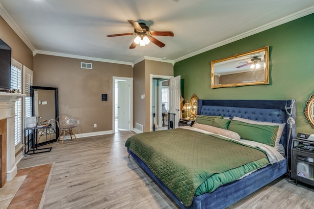 bedroom with crown molding, light hardwood / wood-style flooring, a tile fireplace, and ceiling fan