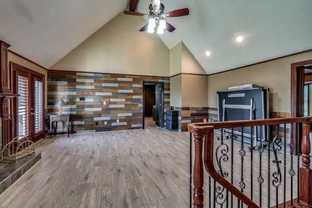 living room with light hardwood / wood-style floors, high vaulted ceiling, tile walls, and ceiling fan