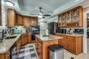 kitchen with black appliances, a center island, ceiling fan, and tasteful backsplash