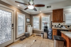 kitchen with ornamental molding, light tile patterned floors, backsplash, and ceiling fan