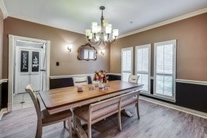 dining room with crown molding, an inviting chandelier, and hardwood / wood-style floors