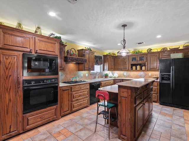 kitchen featuring black appliances, sink, backsplash, a center island, and crown molding