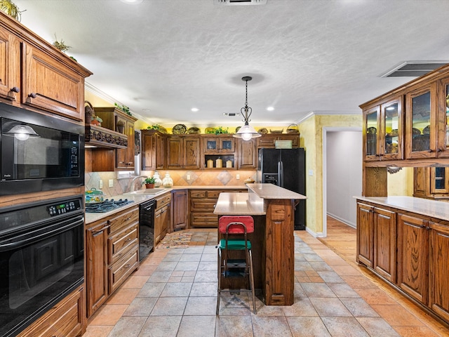 kitchen with ornamental molding, sink, black appliances, a center island, and a kitchen bar