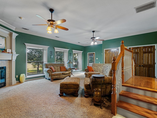 living room with ornamental molding, a tiled fireplace, and ceiling fan