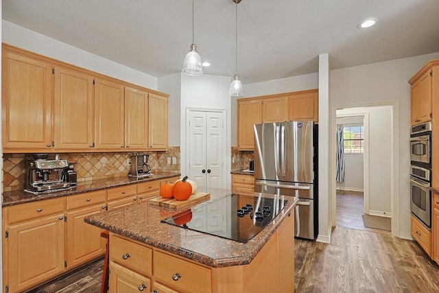 kitchen with a center island, dark wood-type flooring, stainless steel appliances, dark stone counters, and hanging light fixtures