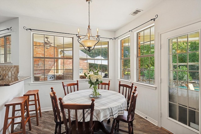 dining area featuring dark wood-type flooring, a healthy amount of sunlight, and a notable chandelier