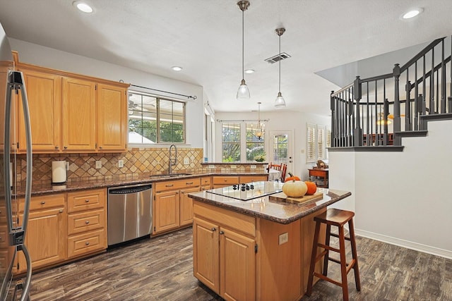 kitchen with decorative light fixtures, a kitchen island, sink, appliances with stainless steel finishes, and dark wood-type flooring