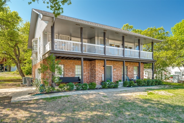 rear view of property with a yard, a balcony, and central AC unit