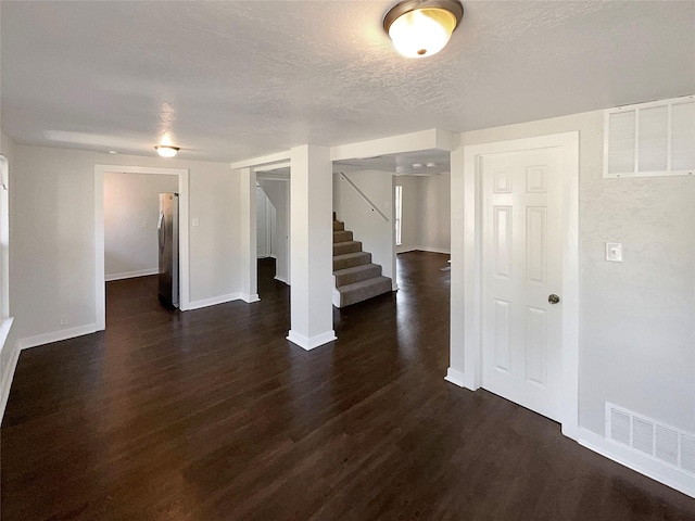 117 Avondale Ave, Azle, TX 76020 - unfurnished room featuring dark wood finished floors, a textured ceiling, visible vents, stairway, and baseboards