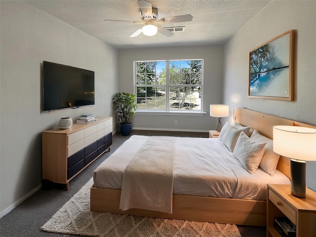 bedroom with dark colored carpet, ceiling fan, and a textured ceiling