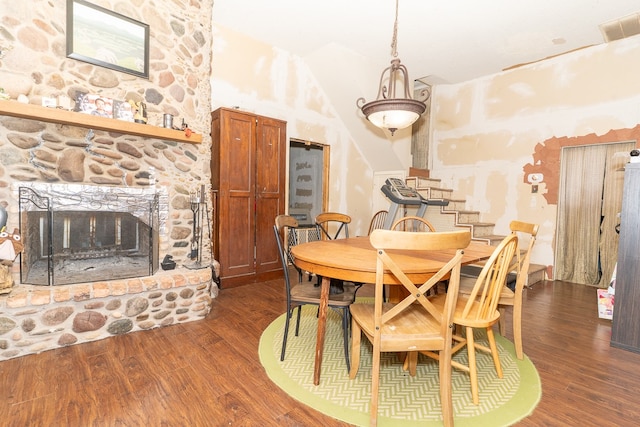 dining space with a stone fireplace and dark wood-type flooring