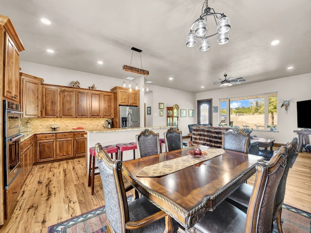 dining area featuring ceiling fan with notable chandelier and light hardwood / wood-style flooring