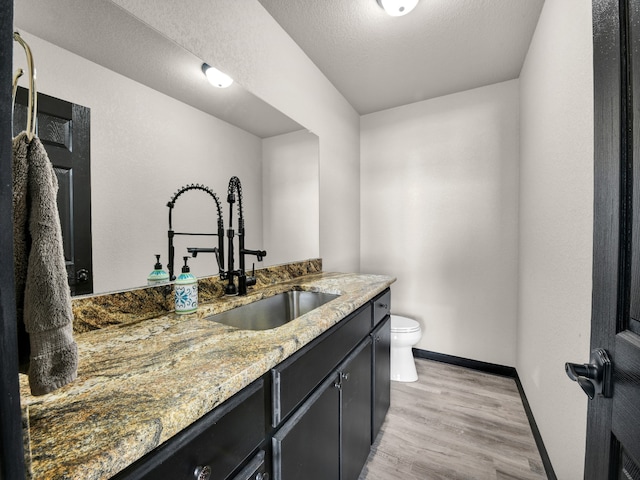 bathroom featuring hardwood / wood-style floors, vanity, a textured ceiling, and toilet