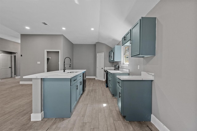 kitchen with a center island with sink, baseboards, light wood-style flooring, appliances with stainless steel finishes, and a sink