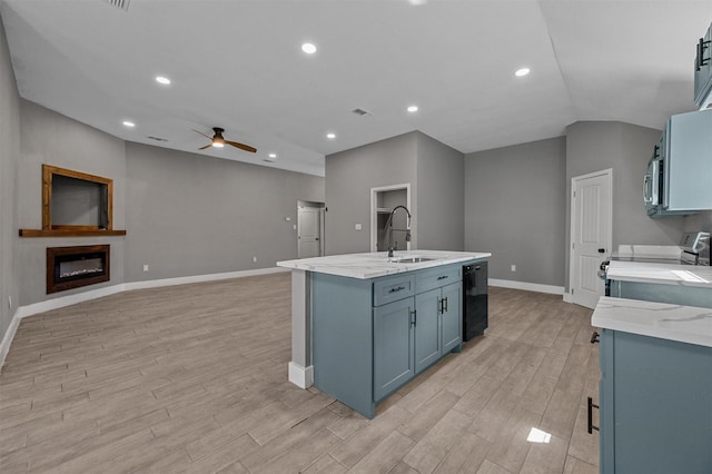 kitchen featuring a glass covered fireplace, ceiling fan, appliances with stainless steel finishes, light wood-type flooring, and a sink