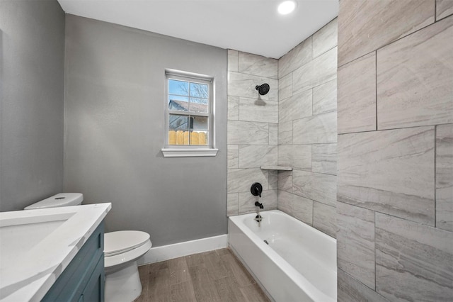 bathroom with shower / washtub combination, toilet, vanity, wood finished floors, and baseboards