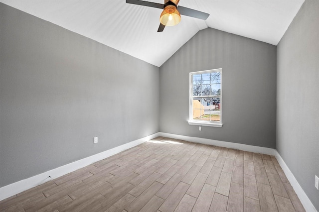 empty room with a ceiling fan, vaulted ceiling, baseboards, and wood finished floors