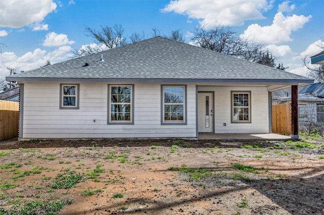 back of house with a patio, roof with shingles, and fence