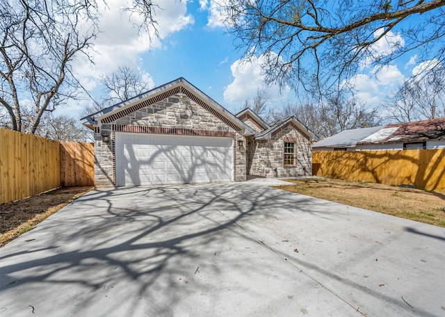 view of front facade with stone siding, fence, concrete driveway, and an attached garage