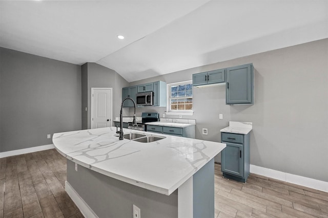 kitchen featuring light wood-style flooring, vaulted ceiling, stainless steel appliances, and a sink