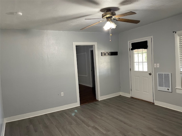 spare room featuring dark hardwood / wood-style floors, heating unit, and ceiling fan