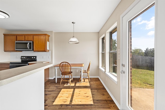 1108 E E Park, Lindale, TX 75771 - kitchen featuring range with electric stovetop, stainless steel microwave, brown cabinetry, dark wood-style flooring, and decorative backsplash