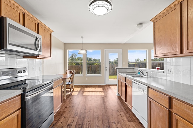 kitchen with pendant lighting, sink, backsplash, appliances with stainless steel finishes, and dark hardwood / wood-style flooring