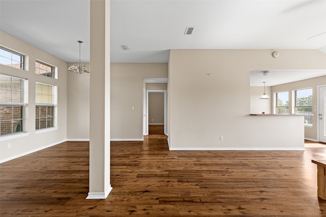 unfurnished living room with a notable chandelier, dark hardwood / wood-style floors, and a wealth of natural light