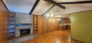 unfurnished living room with vaulted ceiling with beams, ceiling fan, a fireplace, and hardwood / wood-style flooring