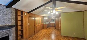 149 NW Suzanne Ter, Burleson, TX 76028 - unfurnished living room featuring ceiling fan, wood finished floors, and a stone fireplace