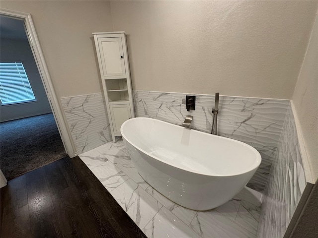 bathroom featuring a bath, tile walls, and wood-type flooring