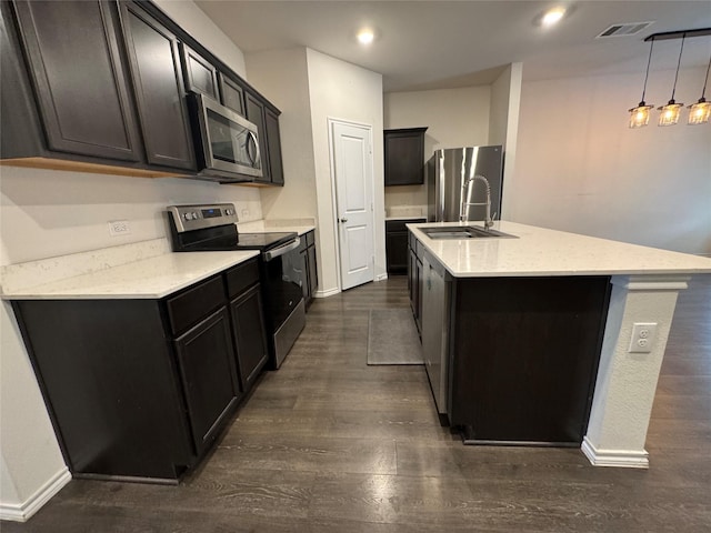 kitchen featuring an island with sink, stainless steel appliances, dark hardwood / wood-style floors, pendant lighting, and sink