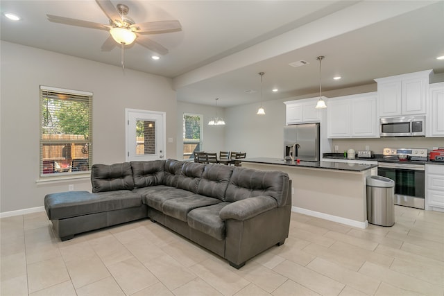 tiled living room with ceiling fan with notable chandelier