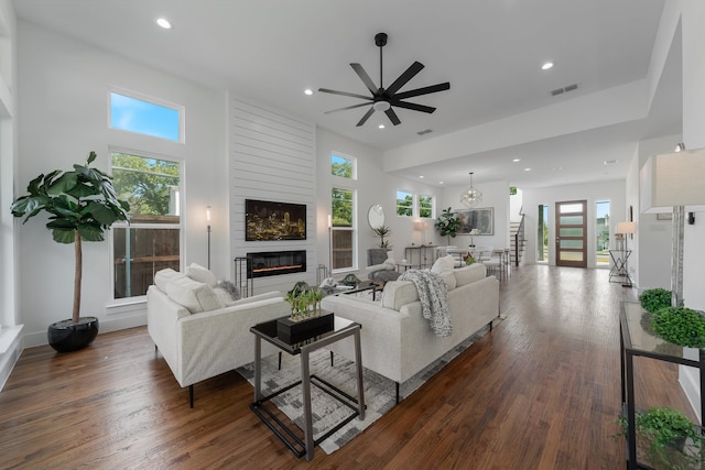 living room featuring ceiling fan, a towering ceiling, and dark hardwood / wood-style flooring