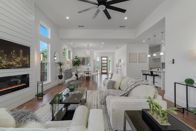 living room with ceiling fan with notable chandelier, a wealth of natural light, and wood-type flooring