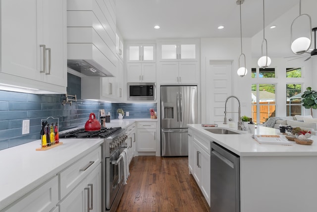 kitchen with stainless steel appliances, custom range hood, sink, pendant lighting, and white cabinetry