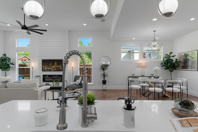 living room featuring a large fireplace, plenty of natural light, wood-type flooring, and ceiling fan