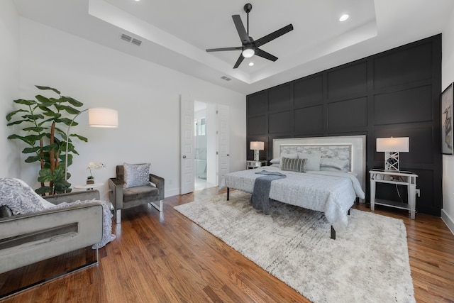 bedroom featuring ceiling fan, a raised ceiling, and hardwood / wood-style floors