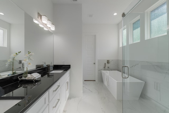 bathroom with a bathing tub, vanity, and tile walls