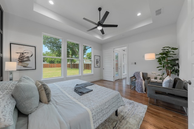 bedroom with ceiling fan, hardwood / wood-style flooring, and a tray ceiling