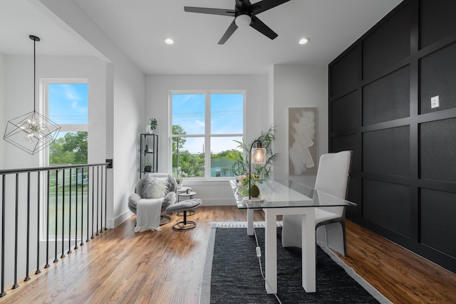 home office with ceiling fan with notable chandelier and light hardwood / wood-style floors