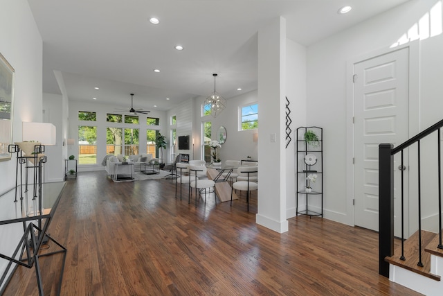 interior space featuring ceiling fan with notable chandelier, a wealth of natural light, and dark hardwood / wood-style floors