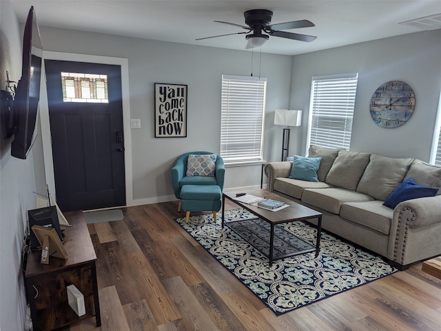 living room featuring dark wood-type flooring, ceiling fan, and a healthy amount of sunlight