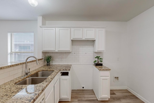 kitchen featuring white cabinetry, sink, light wood-type flooring, and decorative backsplash